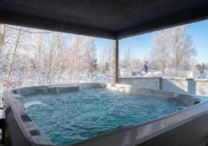 a hot tub on a patio with snow covered trees at Villa West Ellivuori - High Quality 6BR Villa with Jacuzzi in Sastamala
