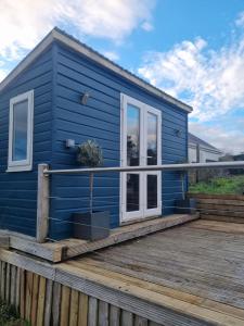 a blue tiny house on a wooden deck at Halwyn View in St Austell