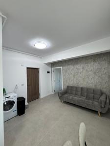 a living room with a couch and a washing machine at DE Apartment in Rădăuţi