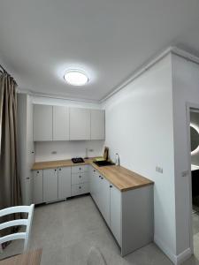 a kitchen with white cabinets and a wooden counter top at DE Apartment in Rădăuţi