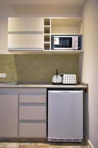 a small kitchen with a microwave and a refrigerator at Mares Apart Hotel in Mar de Ajó +15 photos