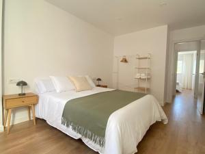 a white bedroom with a large bed and a wooden floor at A Ribeira - BoaOnda in Cee