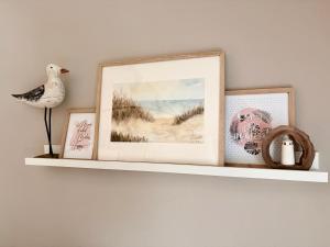 a shelf with three pictures and a bird on it at Strandbrise App 17 in Neuhaus