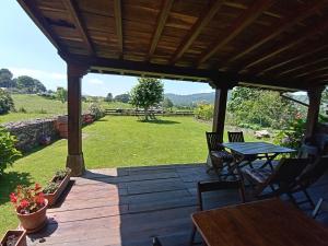 a wooden deck with a table and chairs on a field at El Espesedo, casa rural a 5km del Parque de Cabárceno in Argomilla