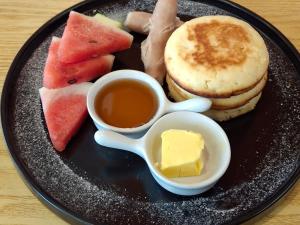 a plate of breakfast food with syrup and watermelon and cheese at Wanderlust Bed and Breakfast Puerto Princesa in Puerto Princesa City