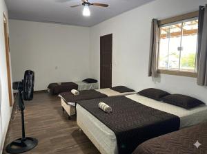a bedroom with two beds and a fan at Suites Lara Jackson in Saquarema +30 photos