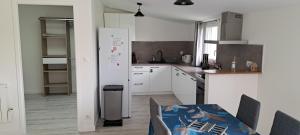 a kitchen with a table and a white refrigerator at Gîte du Chemin vert in Taugon +7 photos