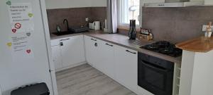 a kitchen with white cabinets and a black stove at Gîte du Chemin vert in Taugon