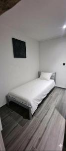 a bed in a room with white walls and wooden floors at Chez fina in Ath