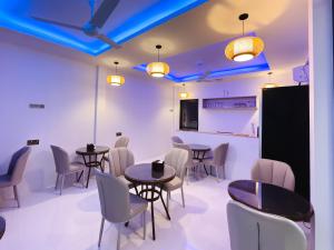 a dining room with tables and chairs and blue lights at Silver Bay Kamadhoo in Kamadhoo