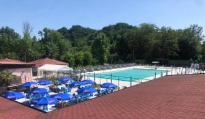a swimming pool with blue umbrellas and chairs at Quadrifoglio Center in Ameno