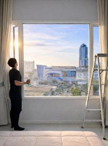 a woman looking out of a window at a city at The Sriracha Residence in Si Racha