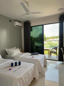 a hotel room with two beds and a balcony at Silver Bay Kamadhoo in Kamadhoo