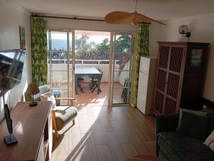 a living room with a couch and a table and a balcony at TROPIC Appartements PREMIUM village vacances vue mer Guadeloupe St Anne avec piscine in Sainte-Anne