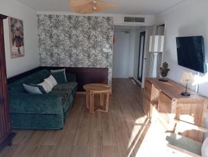 a living room with a green couch and a table at TROPIC Appartements PREMIUM village vacances vue mer Guadeloupe St Anne avec piscine in Sainte-Anne