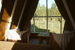 a bedroom with a large window and a bed and a table at Refúgio Fortaleza - Cabana Physalis in Cambará