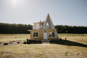 a small house with a triangular roof in a field at Refúgio Fortaleza - Cabana Physalis in Cambará