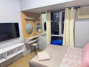 a bedroom with a bed and a tv and a window at Budget Friendly Centrio Tower Studio Unit PoolView in Cagayan de Oro