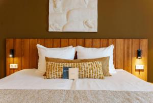 a bedroom with a bed with white sheets and pillows at Boutique Hotel Texel in De Cocksdorp