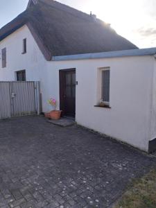 a white house with a door and a potted plant at Fewo Helga in Glowe +4 photos