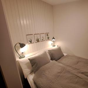 a bedroom with a bed with two lamps on it at Cute gardenhouse close to Stockholm City in Solna