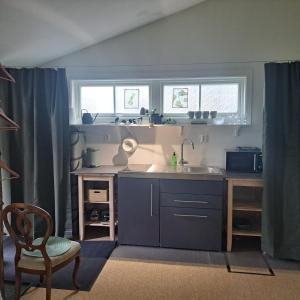 a kitchen with a sink and a table and two windows at Cute gardenhouse close to Stockholm City in Solna