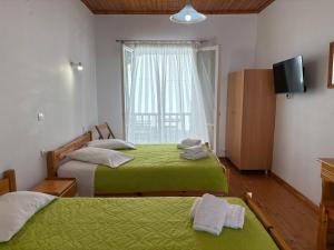 a bedroom with two beds with green sheets and a window at Elena Rooms in Agios Nikitas