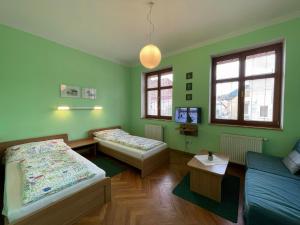 a green room with two beds and a couch at Penzion Andrej in Ružomberok