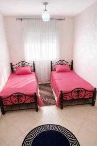a bedroom with two beds with pink sheets and a window at Cozy appartement à Mohammedia in Mohammedia