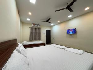 ein Schlafzimmer mit Bett und Flachbildfernseher in der Unterkunft Aathidya Lodge in Ādoni