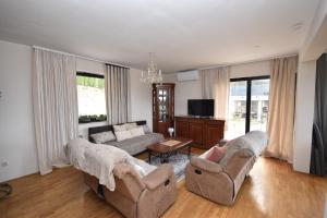 a living room with two couches and a tv at apartmaji LEJARDIN in Škofljica
