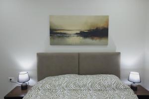 a bed with two lamps and a painting on the wall at The Swan Nest 2 in Pogradec