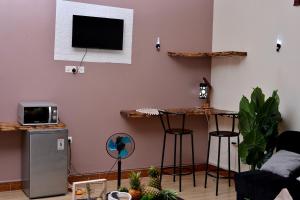 a living room with a tv and two bar stools at Peryn Suites Kinubi, Hoima City, Uganda in Hoima
