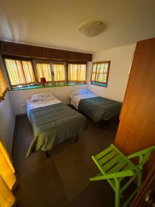 a room with two beds and a green chair at Camping Roma in Ventimiglia