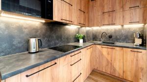 a kitchen with wooden cabinets and a sink at Apartament Komfort Lux in Karpacz +3 photos