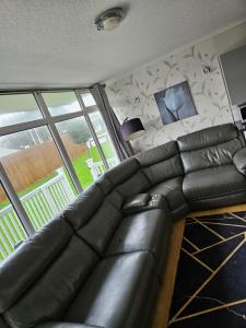 a leather couch in a living room with a window at 116 cherry park in Chapel Saint Leonards