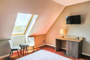 a room with a desk and chairs and a tv at Hotel De La Digue in Le Mont Saint Michel