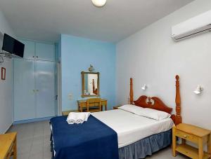 a bedroom with a bed with a blue wall at Dolphin Hotel in Skopelos Town