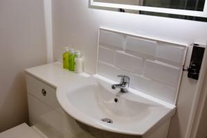 a white bathroom with a sink and a mirror at Stylish Studio with Parking in Doncaster in Doncaster