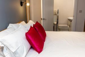 a white bed with two red pillows on it at Stylish Studio with Parking in Doncaster in Doncaster +12 photos