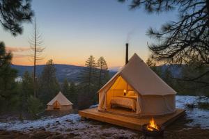 a tent with a bed and a fire in the snow at Genesis Mountain Farm in Sandpoint +14 photos