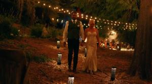 a bride and groom walking down a path with lights at Genesis Mountain Farm in Sandpoint