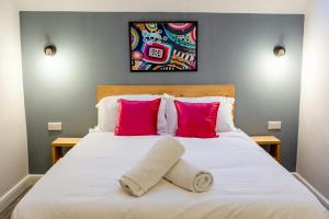 a bedroom with a white bed with two pink pillows at Loft-Style Studio with Skylights and Parking in Doncaster