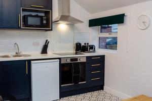 a kitchen with black and white appliances and a clock at Loft-Style Studio with Skylights and Parking in Doncaster +5 photos