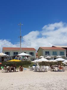 un grupo de personas sentadas en una playa con sombrillas en Cabo frio Beira mar Praia do Peró, en Cabo Frío