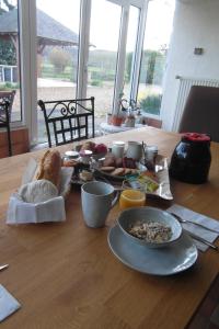 a wooden table with breakfast foods on it at Les Devants De Rupuanne in Bréhémont +6 photos