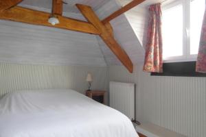 a bedroom with a white bed and two windows at Les Devants De Rupuanne in Bréhémont