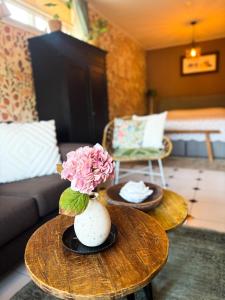 a living room with a table with a vase with flowers at Het Ankertje (Oosterhaven) in Medemblik