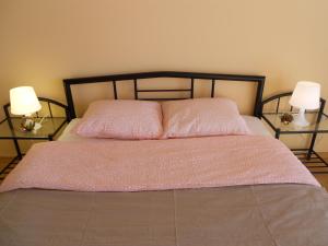 - une chambre avec un lit avec un couvre-lit rose et deux lampes dans l'établissement Апартамент Мур, à Sofia
