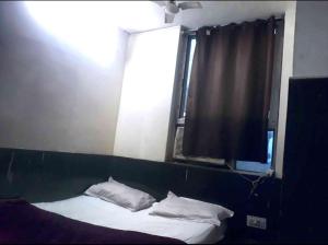 a bed with white pillows in a room with a window at Hotel Mahi in Jaipur